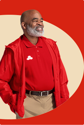 A bearded State Farm agent in red polo shirt and pullover smiles.